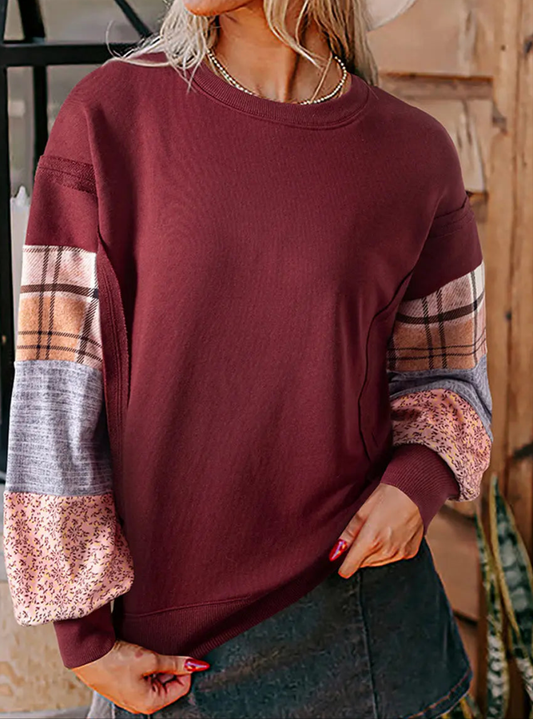 Maroon sweatshirt with plaid sleeves worn by a person indoors.
